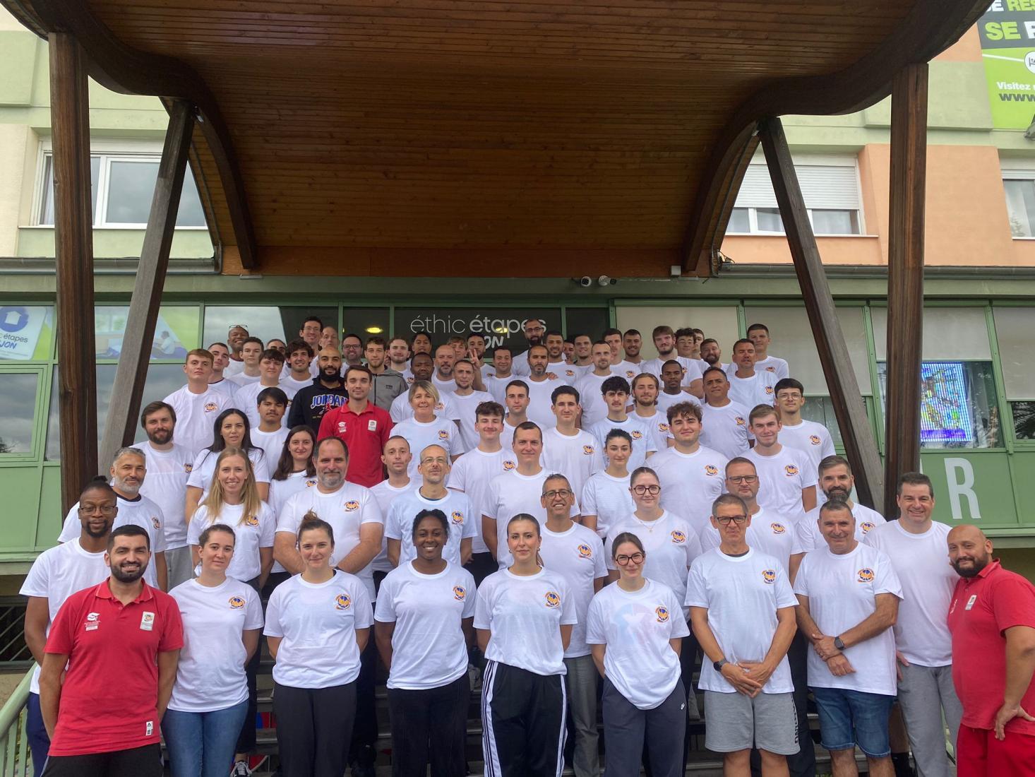 Photo de groupe des arbitres régionaux, en tee-shirt blanc, sur les marches d’un bâtiment.